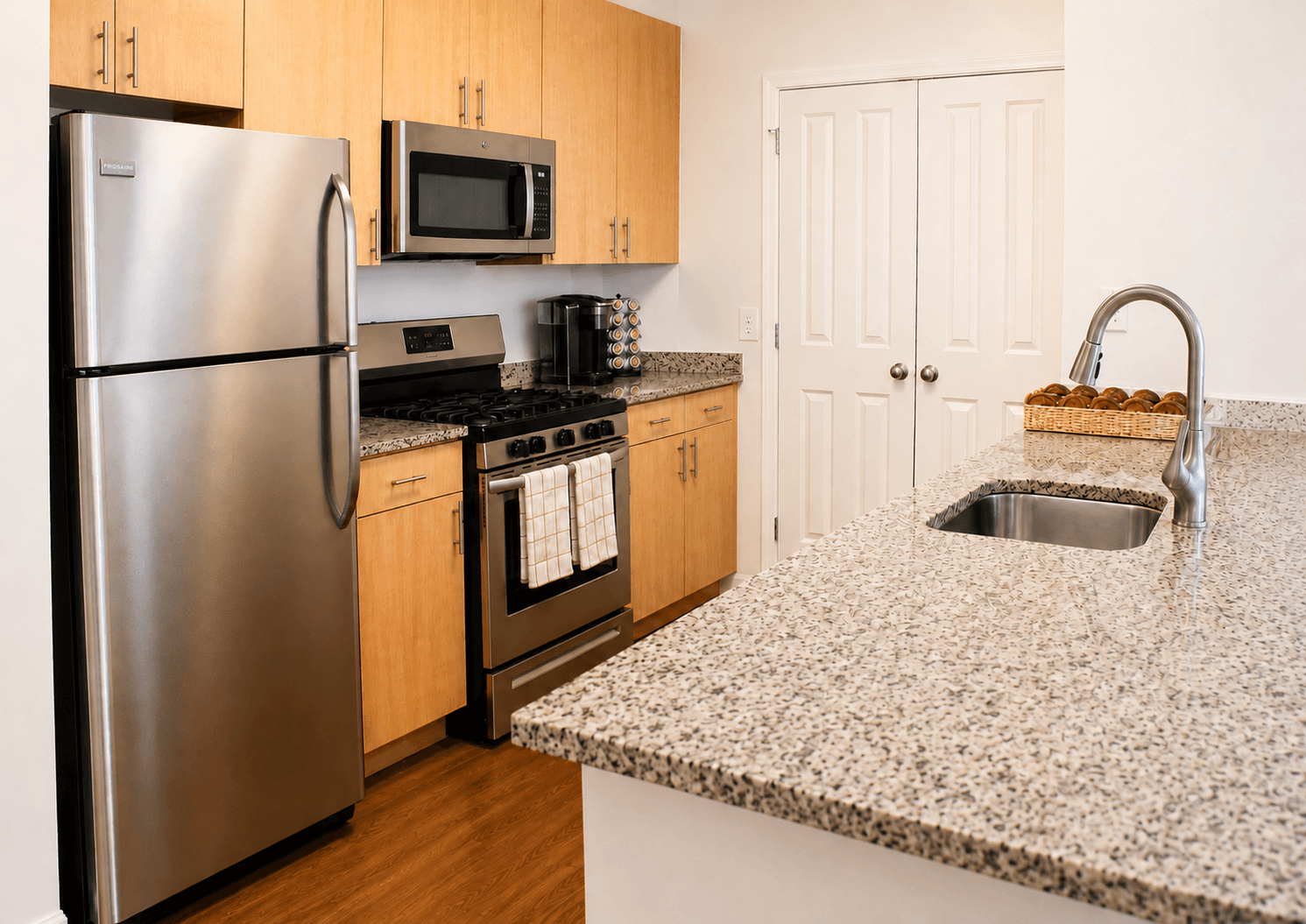 Modern kitchen featuring stainless steel appliances, wooden cabinets, and a granite countertop.