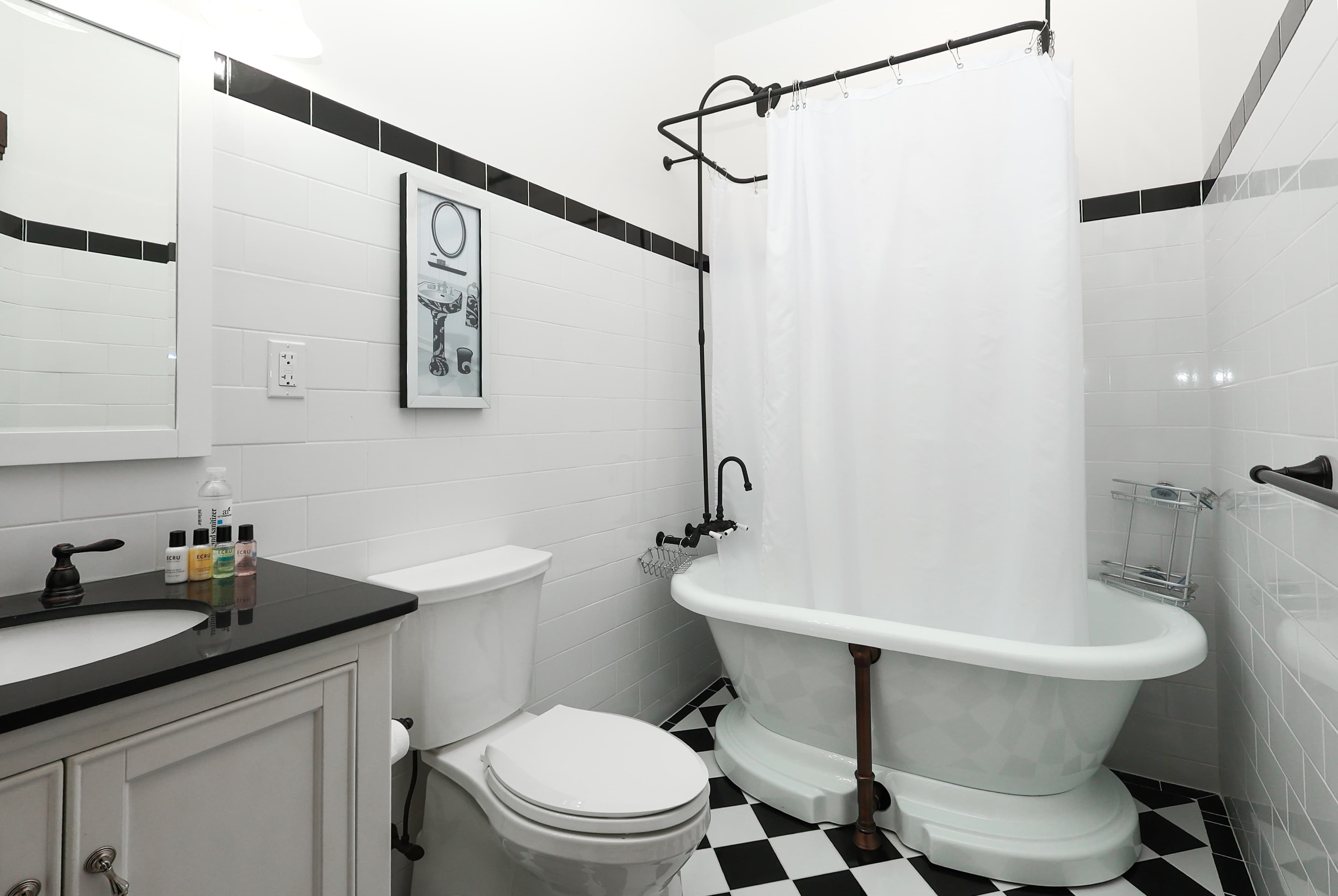 A modern bathroom featuring a black and white color scheme, a freestanding tub, and a shower curtain.