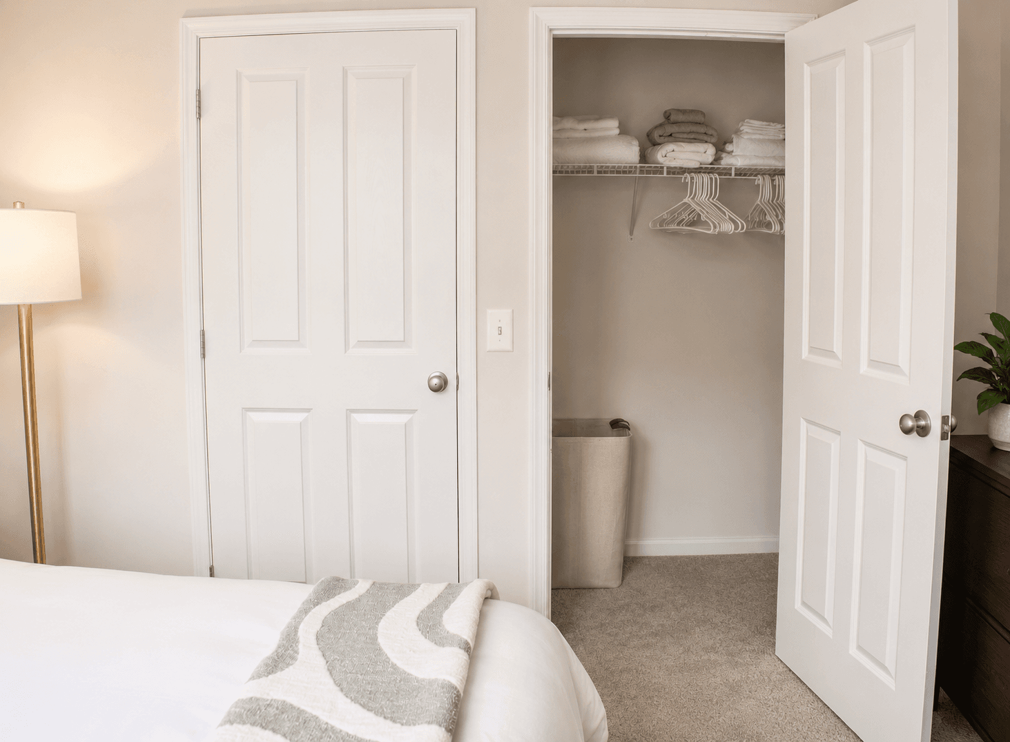 A cozy bedroom featuring a neatly organized closet with towels and a decorative plant nearby.