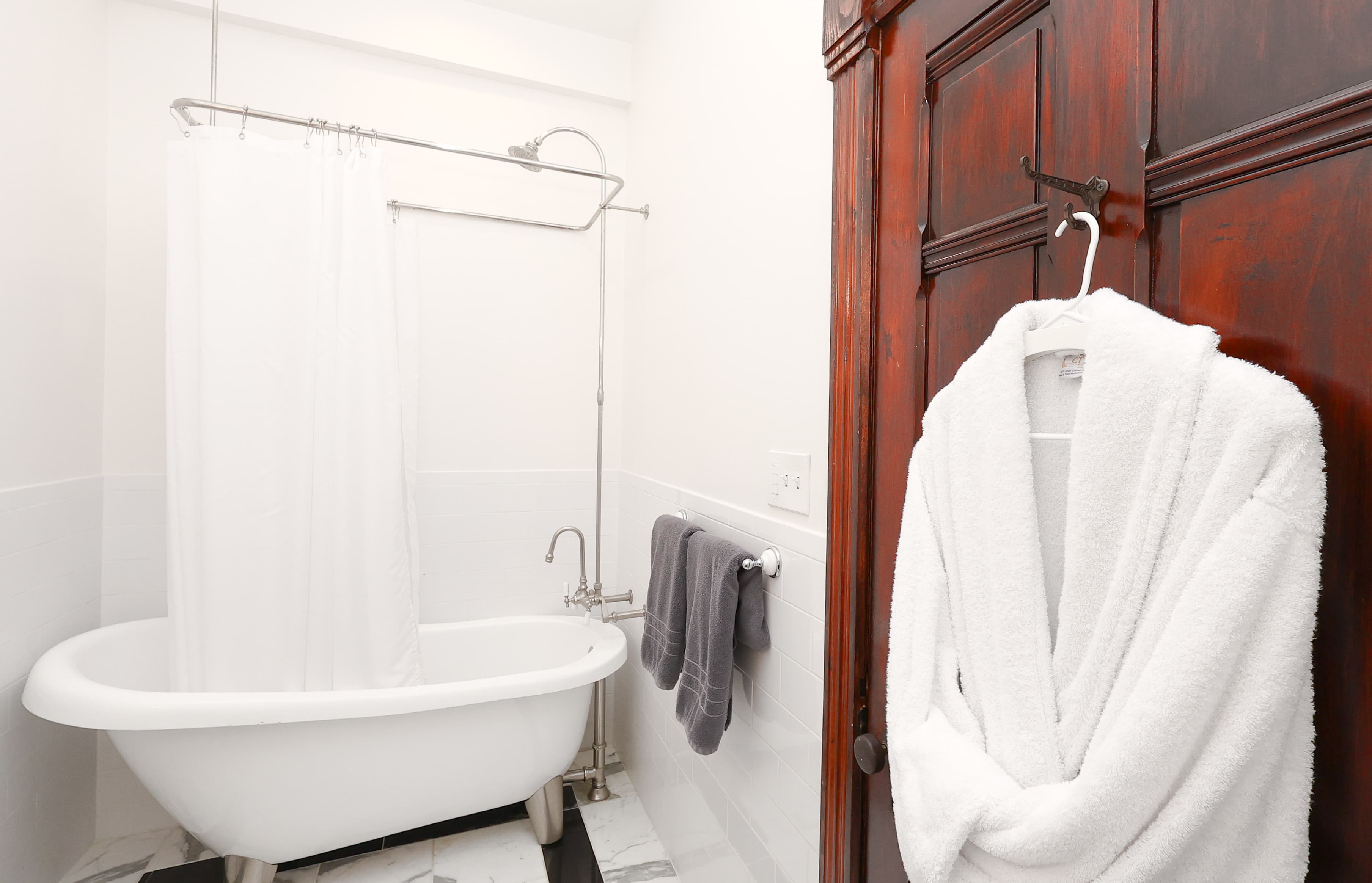 A cozy bathroom featuring a freestanding tub, a shower curtain, and a hanging bathrobe.