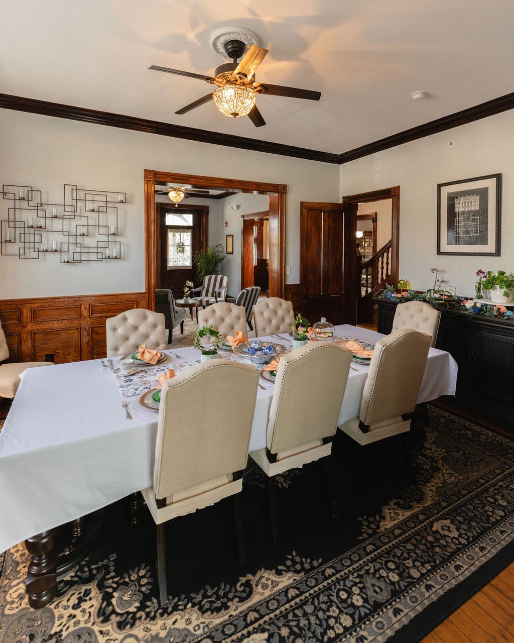 A warmly decorated dining room features an elegantly set table with plush seating and wooden accents.