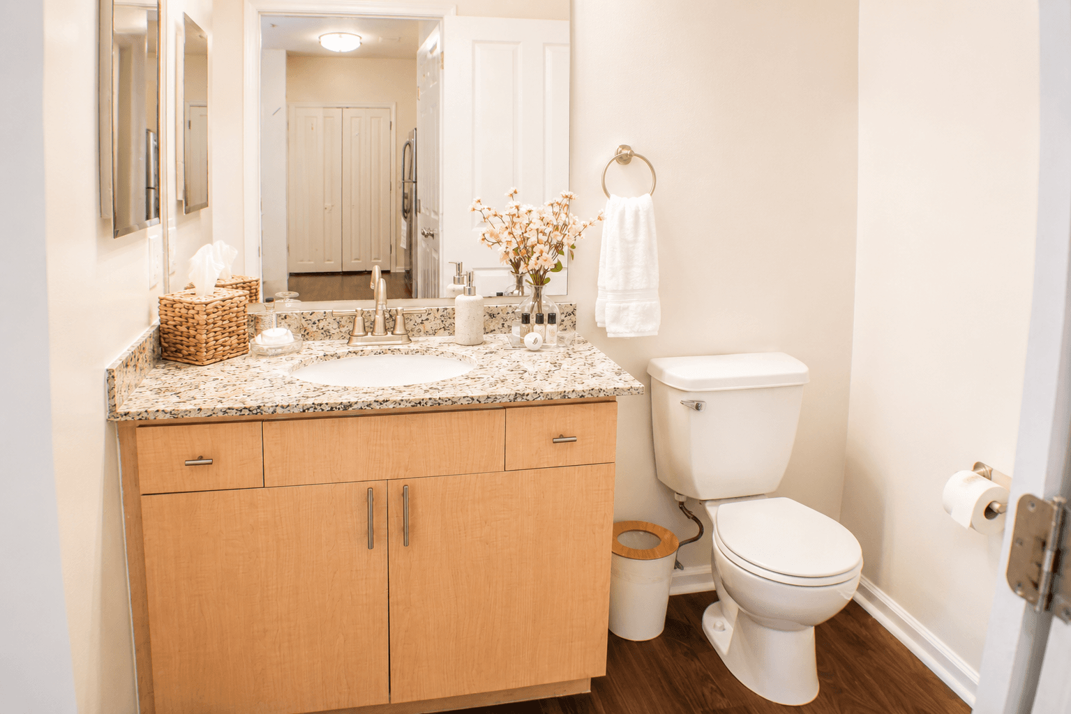 A clean and modern bathroom featuring a granite countertop, sink, wooden cabinet, and toilet.