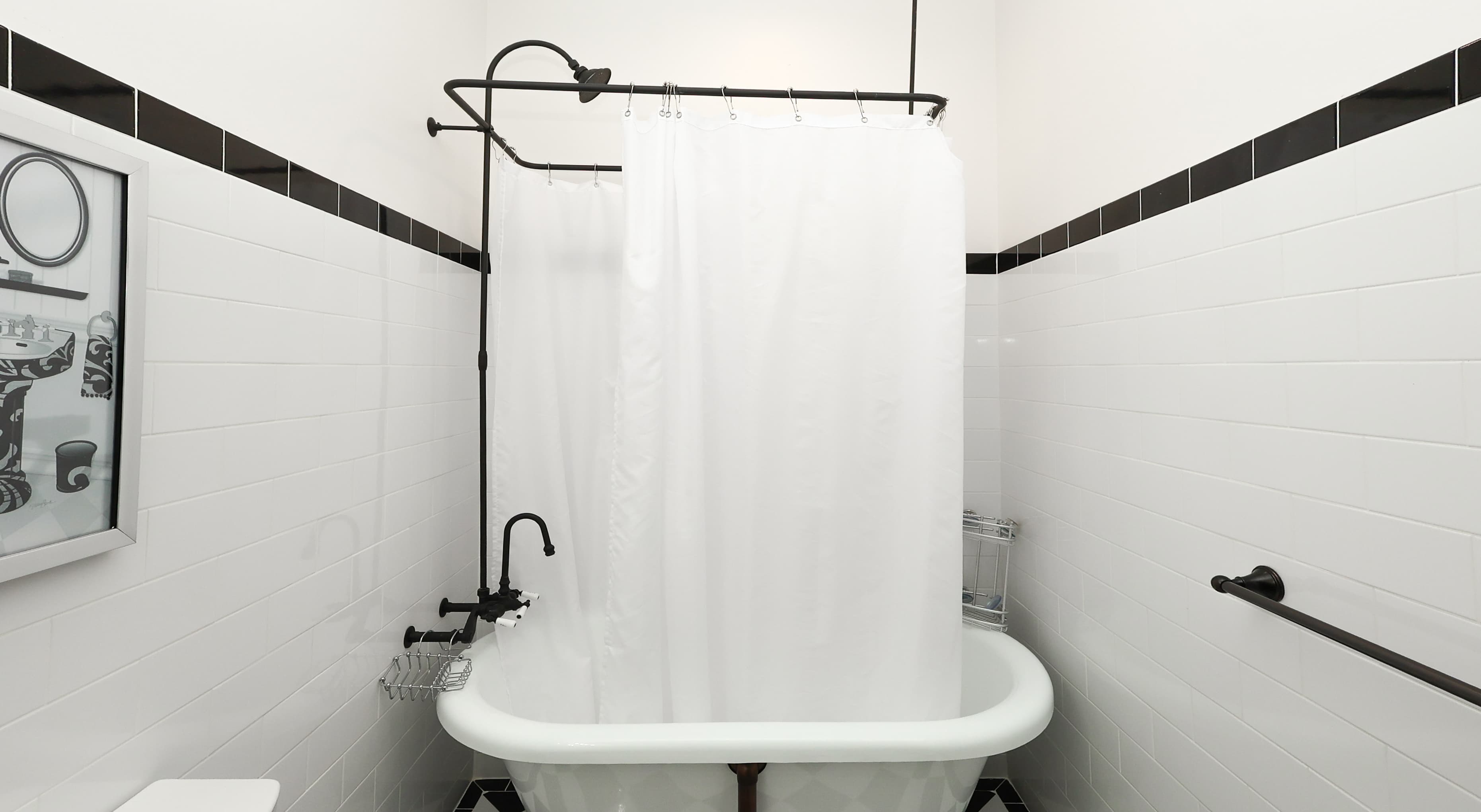 A vintage-style bathroom featuring a white clawfoot bathtub with a shower curtain and black accents.