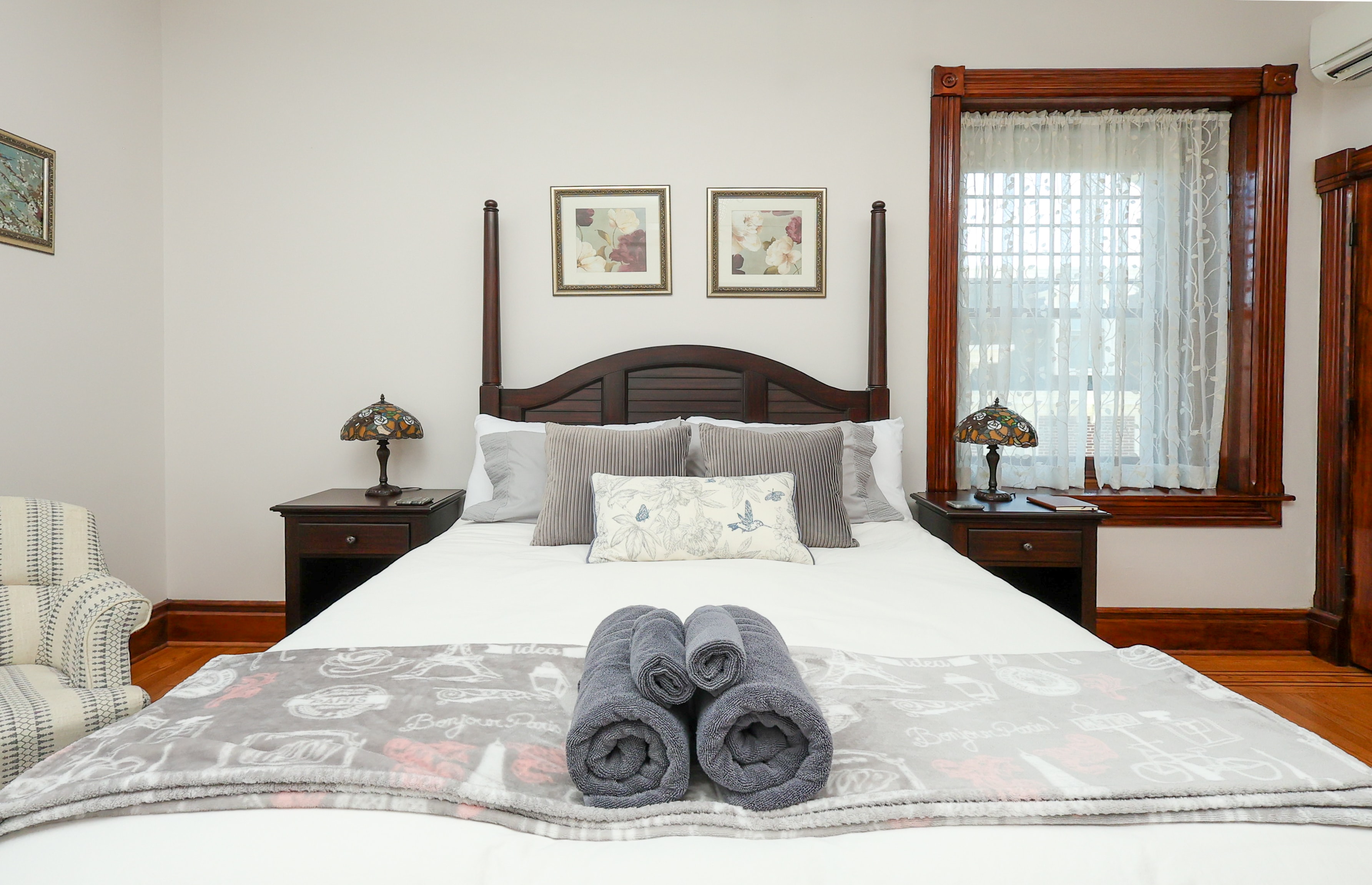 A cozy bedroom featuring a large bed, decorative pillows, a throw blanket, and bedside tables with lamps.