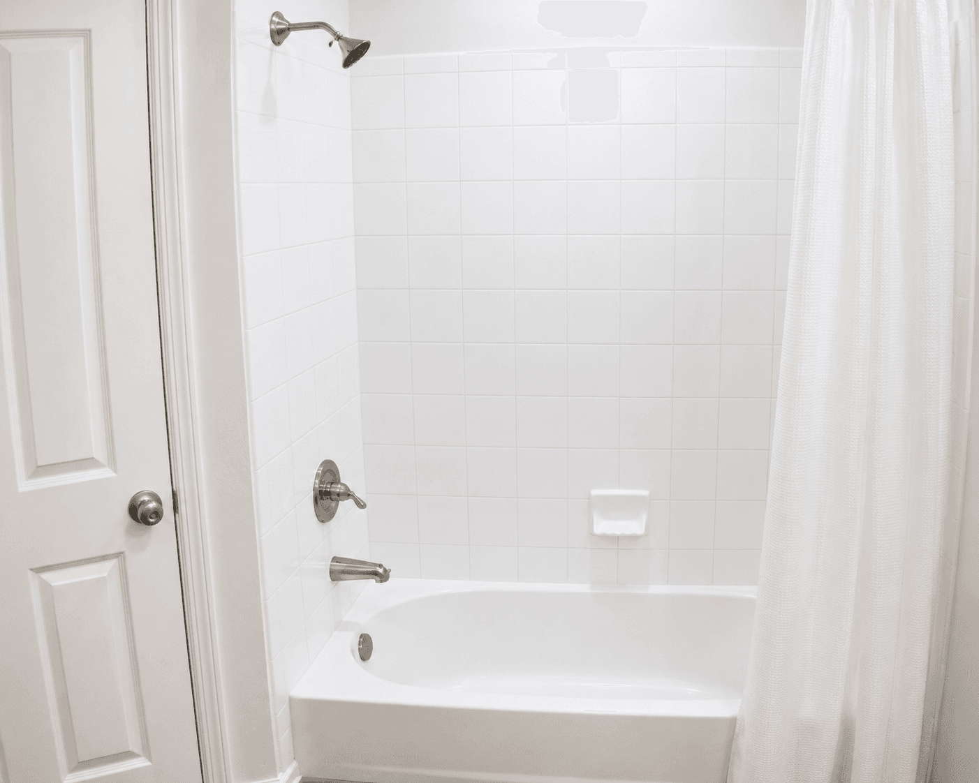 A clean bathroom featuring a white tiled shower with a bathtub and a shower curtain.